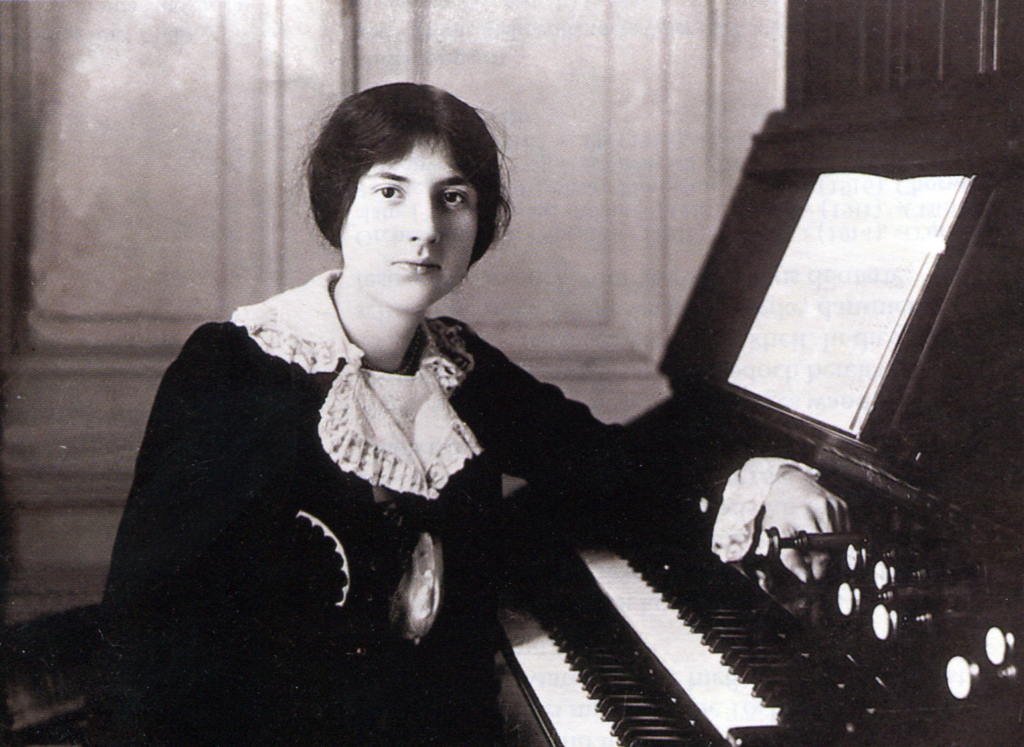 Lili Boulanger an einer Orgel, von der sie sich seitlich weg- und uns zudreht. 